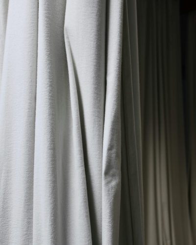 pexels photo 6044838 6044838 Crumpled fabric of curtains with creases hanging on wall in dark empty room